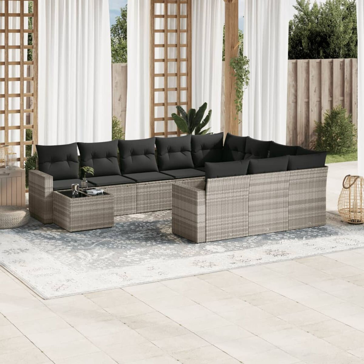 Graues Outdoor-Ecksofa aus Korbgeflecht mit grauen Kissen und Couchtisch. Terrasse.
