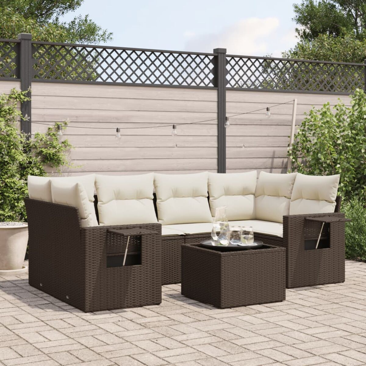 Braunes Korbmöbel-Ecksofa mit cremefarbenen Kissen, einem Tisch und Stühlen auf einer Terrasse.