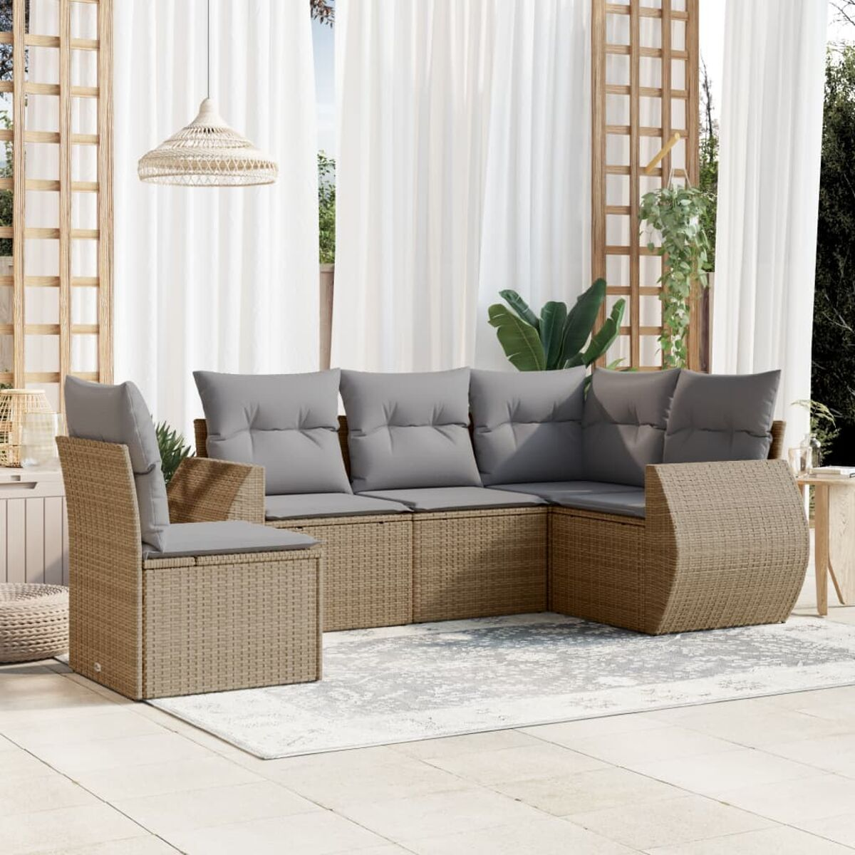 Rattan-Ecksofa mit grauen Kissen auf einer Terrasse. Inklusive Stuhl, Teppich und weißen Vorhängen.