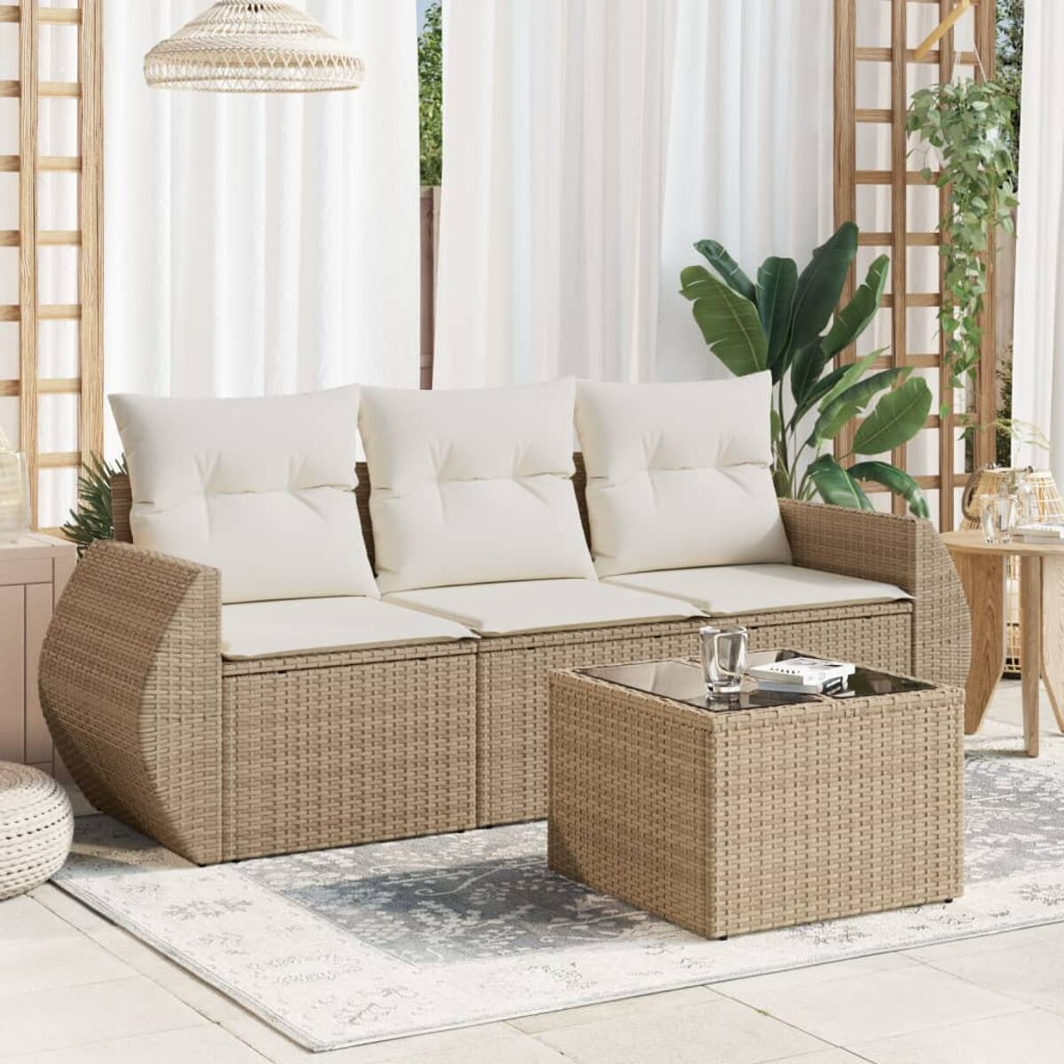 Wicker-Sofa mit weißen Kissen und quadratischem Couchtisch auf einem Teppich auf einer Terrasse.