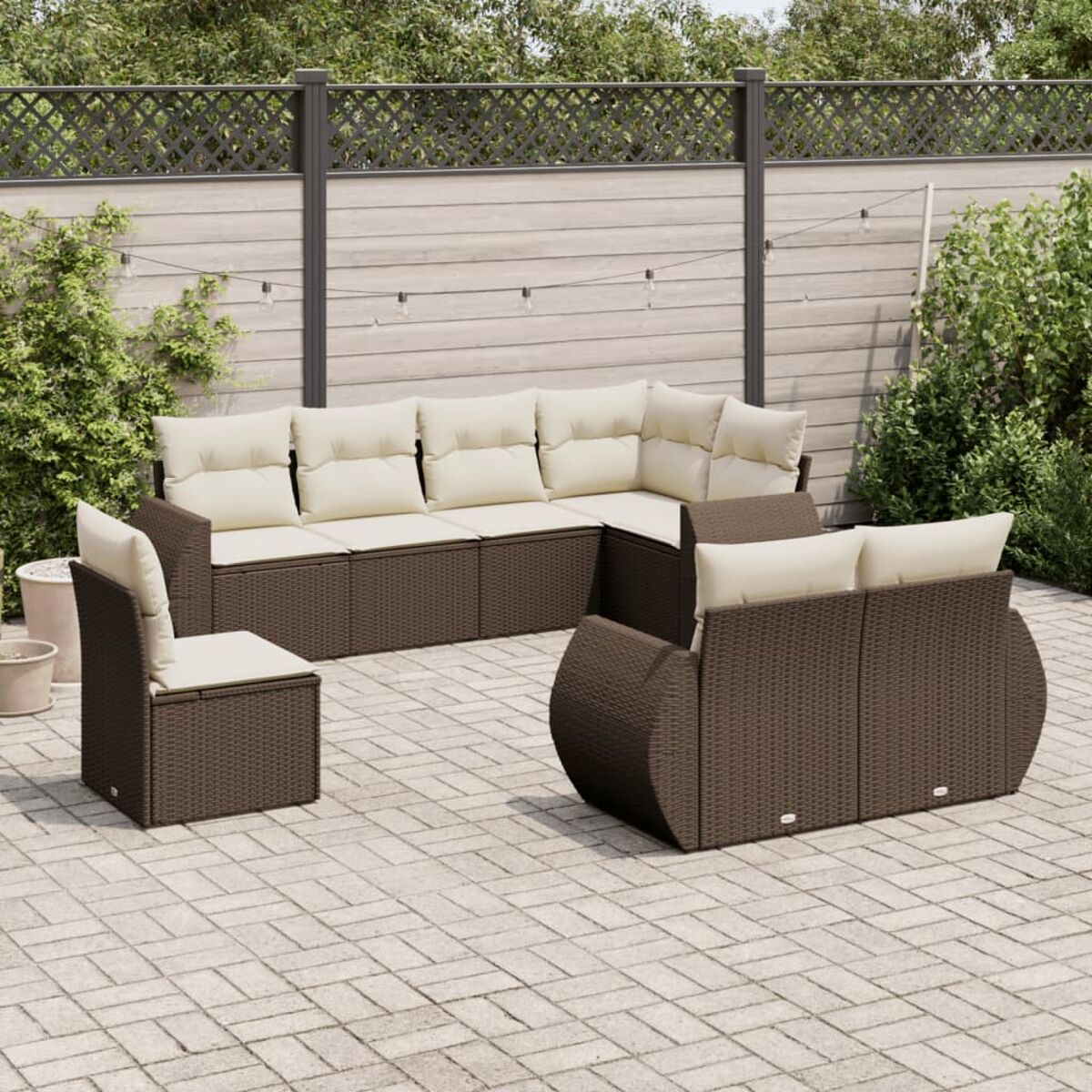 Set divano angolare in rattan marrone con cuscini color crema su un patio in mattoni.