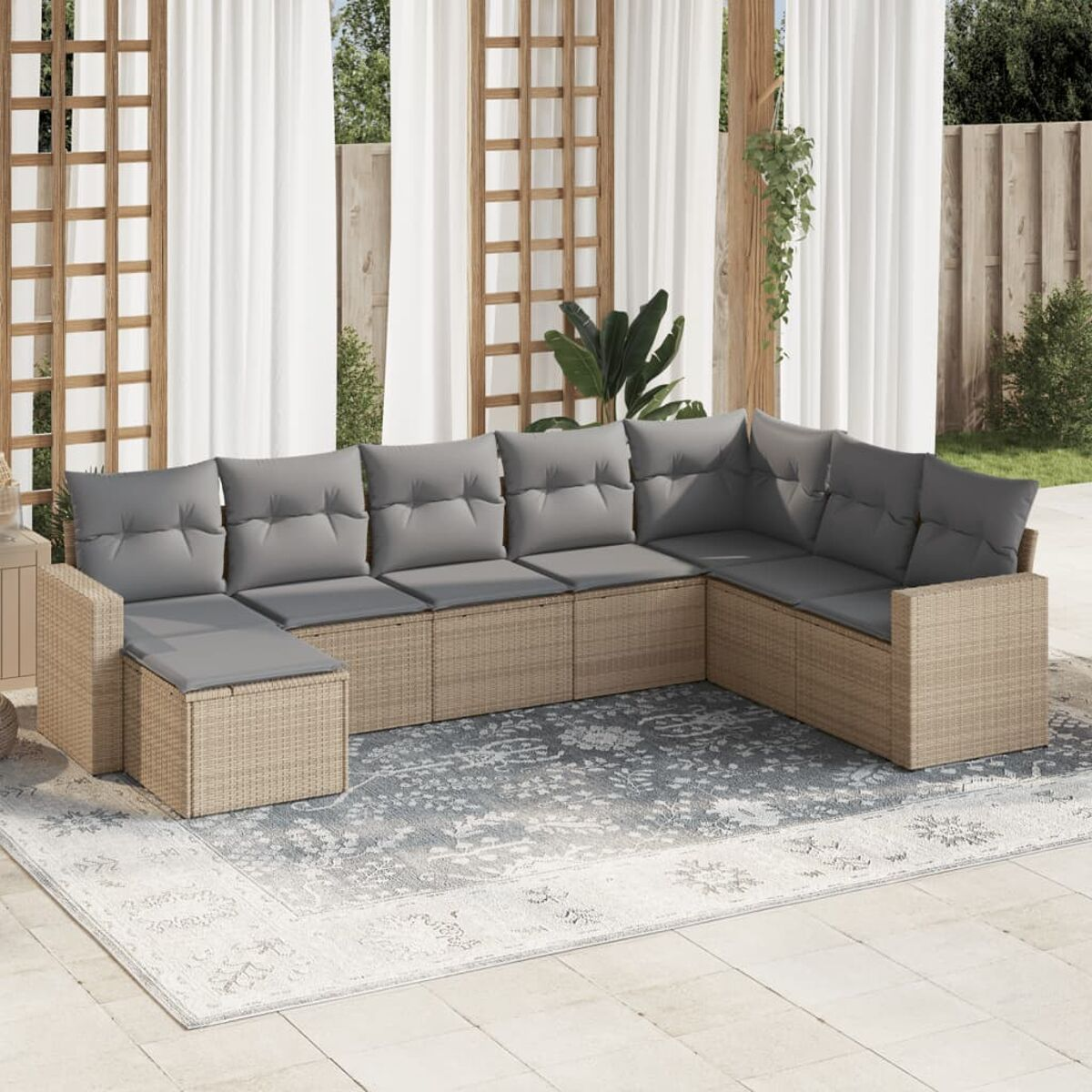 Outdoor-Ecksofa aus Korbgeflecht mit grauen Kissen auf einem gemusterten Teppich. Weiße Vorhänge und Gitter im Hintergrund.