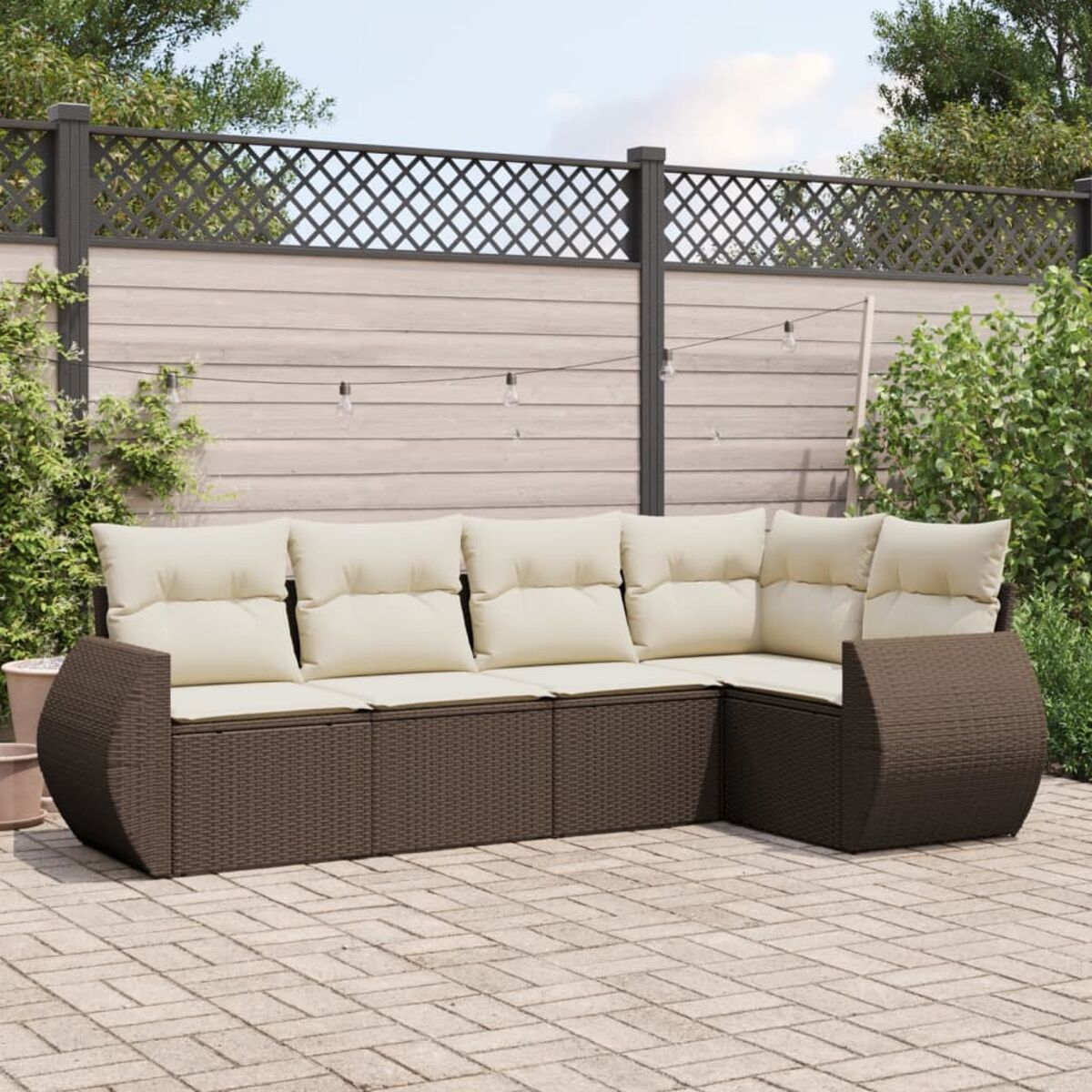 Divano componibile in rattan marrone per esterni con cuscini color crema in un patio.