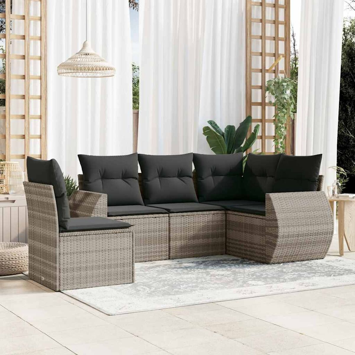 Beige Korbmöbel-Set mit grauen Kissen innen, in der Nähe eines weißen Vorhangs.