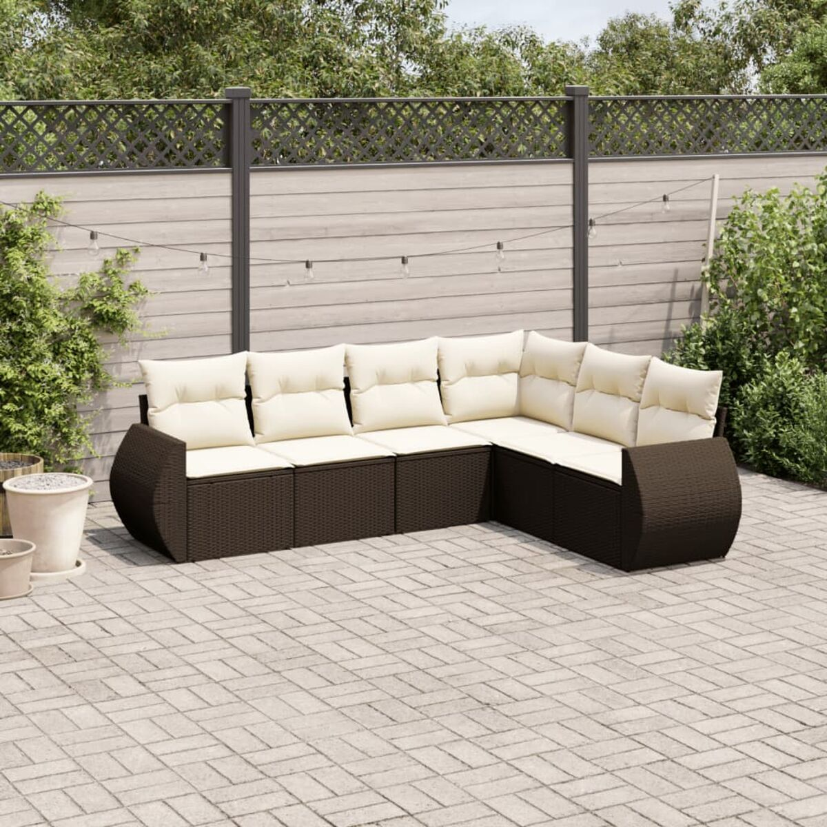 Divano componibile da esterno in rattan marrone con cuscini beige. Design a L sul patio.