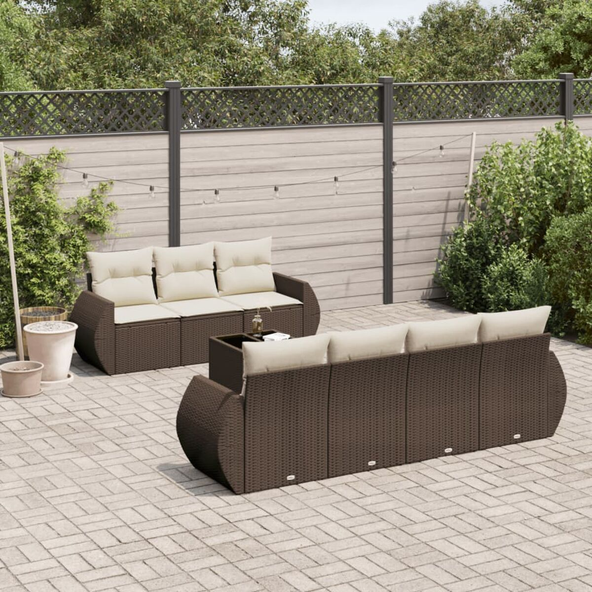 Set divano esterno in rattan marrone con cuscini beige e tavolino.
