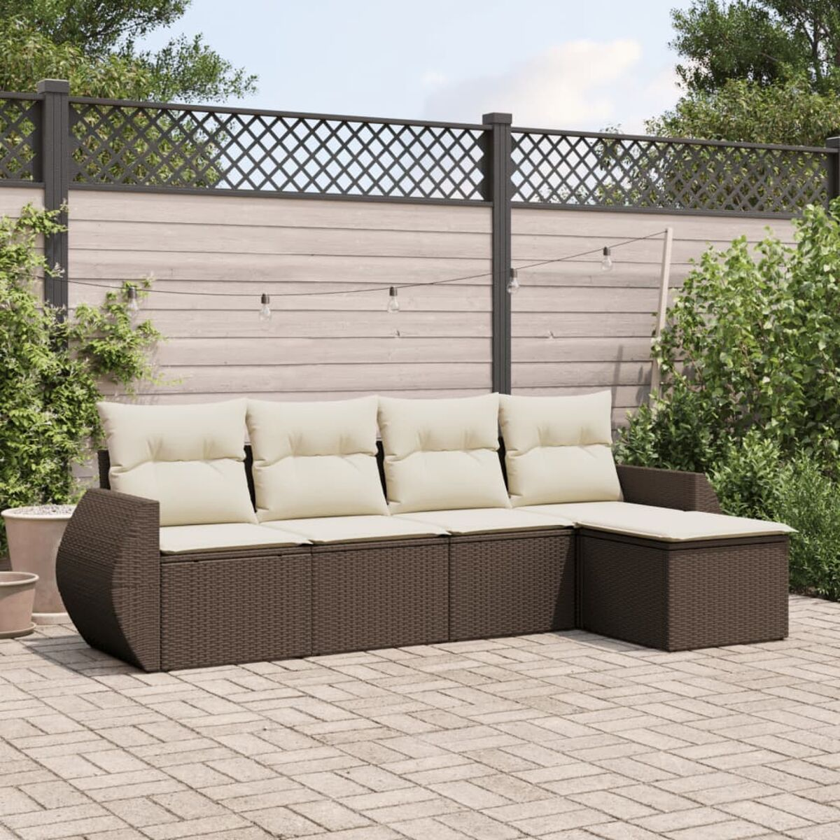 Divano in vimini marrone con cuscini color crema e pouf abbinato su un patio.