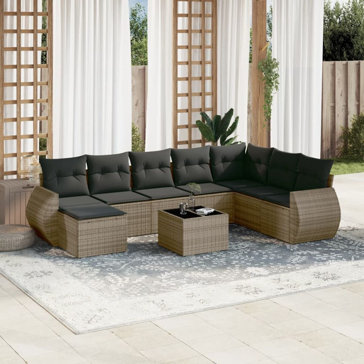 Outdoor-Ecksofa mit dunklen Kissen und Couchtisch auf einem Teppich. Weiße Vorhänge und Holzgitter im Hintergrund.