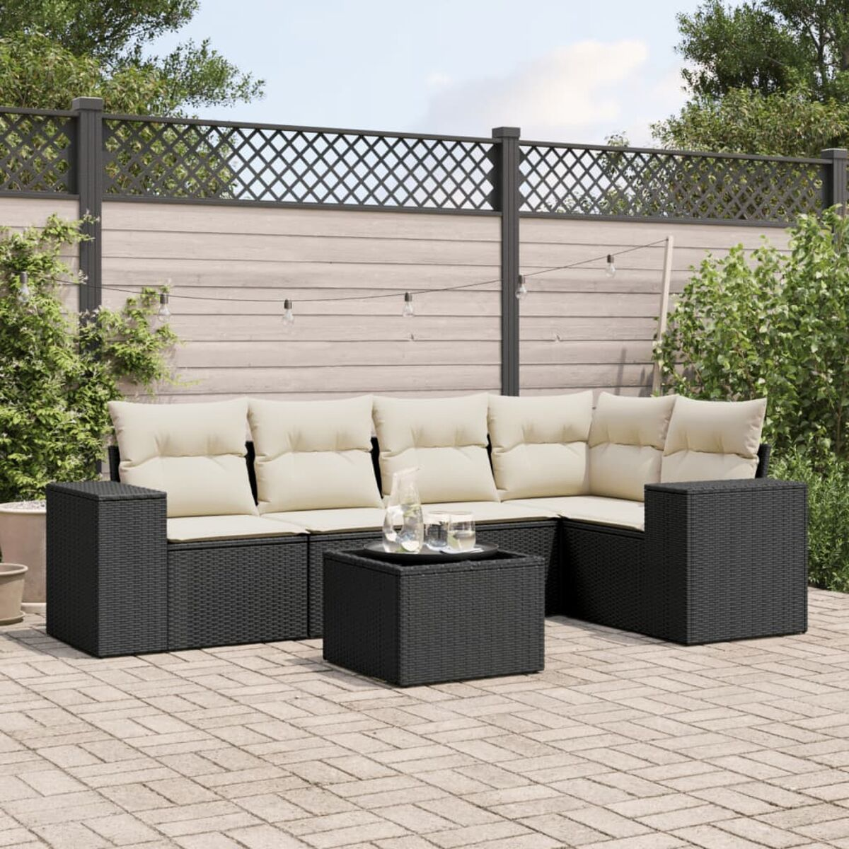 Schwarzes Outdoor-Ecksofa aus Korbgeflecht mit cremefarbenen Kissen, einem quadratischen Tisch und Steinterrasse.