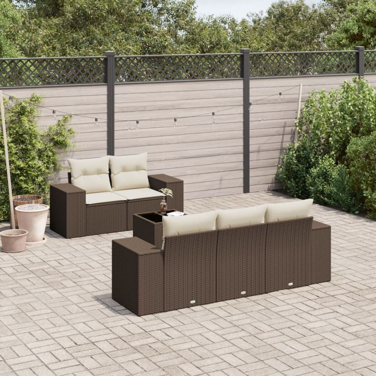 Set divani in vimini marrone con cuscini beige all'aperto.