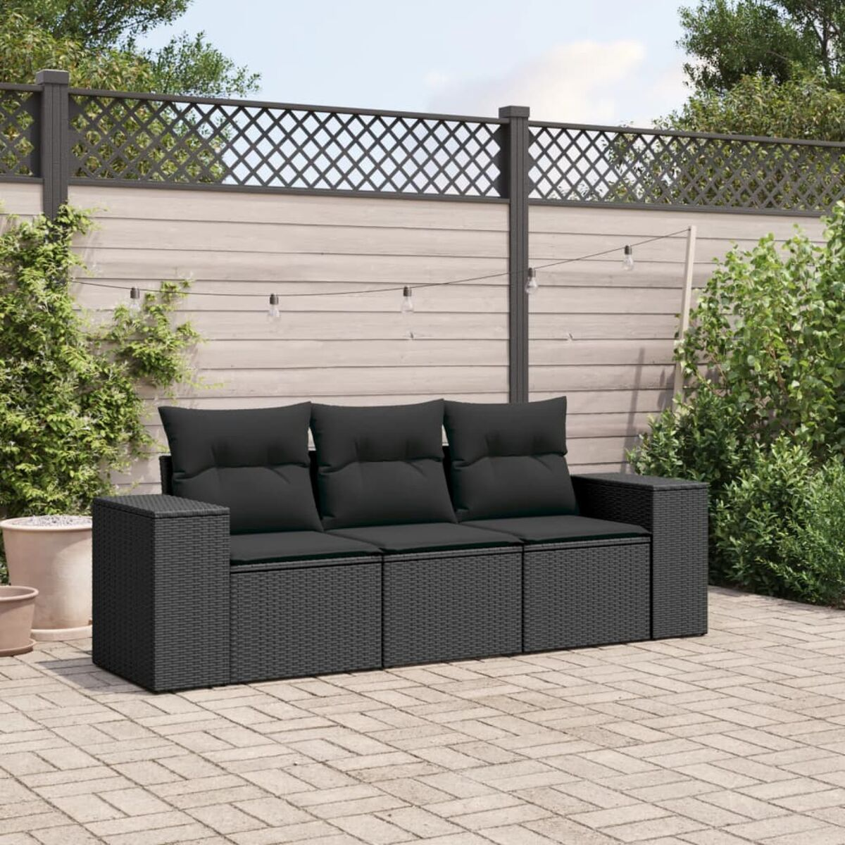 Schwarzes Wicker-Ecksofa mit schwarzen Kissen und Holzarmlehnen auf einer Ziegelterrasse.