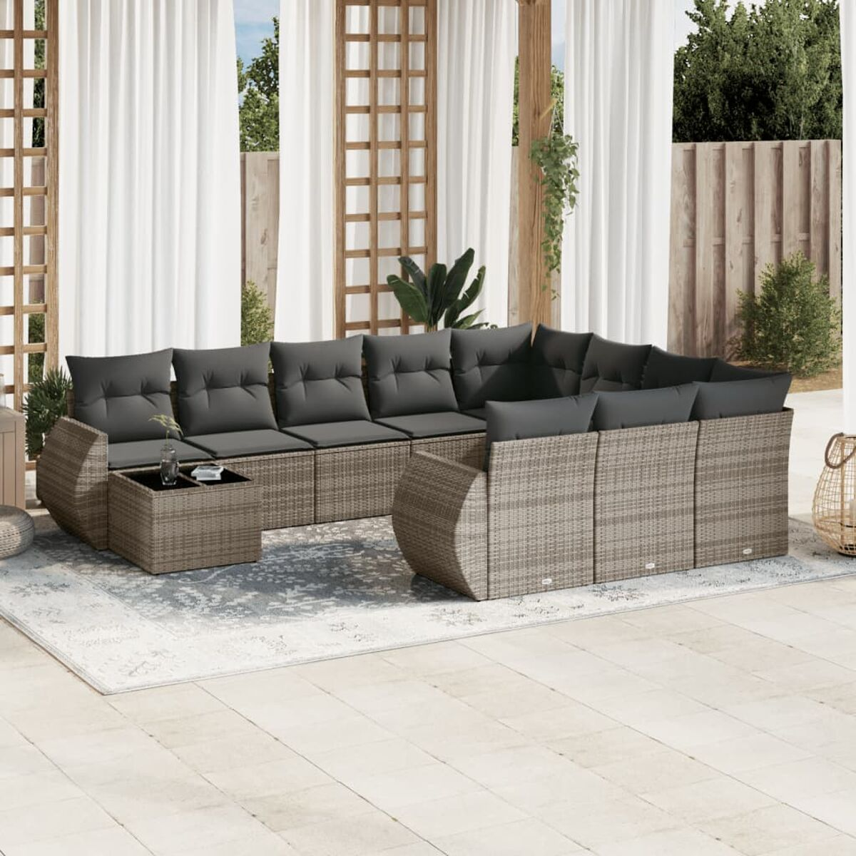 Terrassenmöbel mit grauen Kissen, Couchtisch und Teppich im Freien.