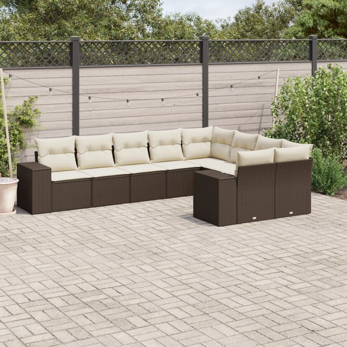 Divano angolare in rattan marrone con cuscini beige su un patio in mattoni.