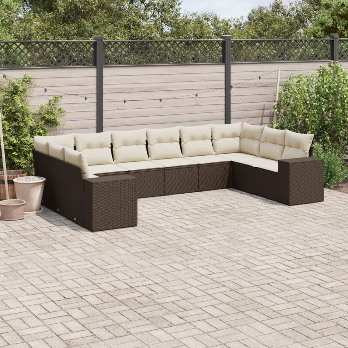Divano componibile da esterno in vimini marrone con cuscini beige, su patio.