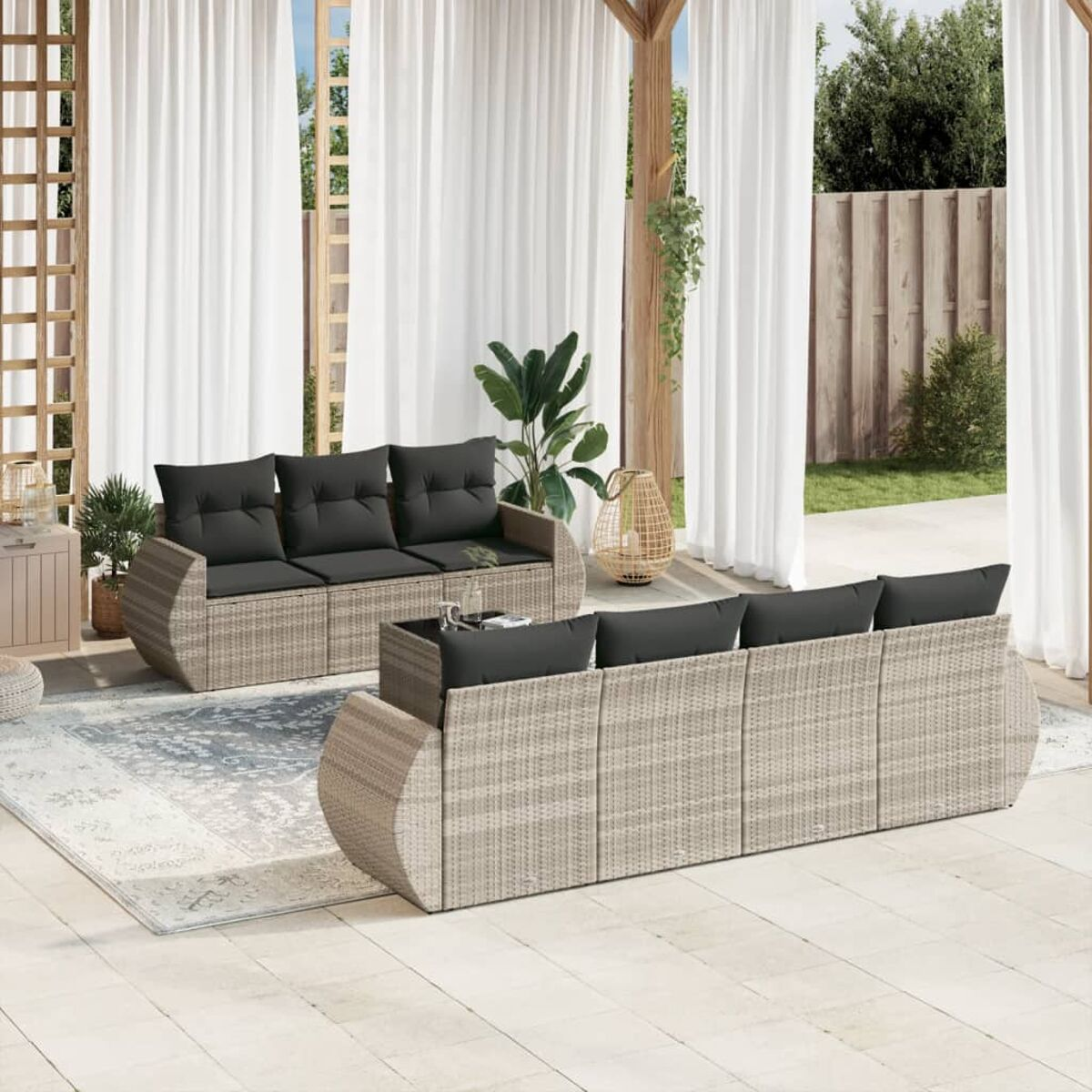 Zwei beigefarbene Korbs Sofas mit schwarzen Kissen auf einem Teppich, Vorhänge im Hintergrund, im Freien.