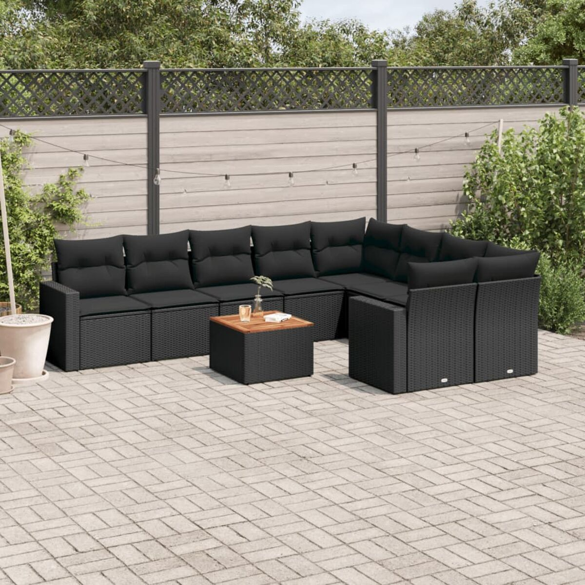 Schwarzes Outdoor-Ecksofa mit schwarzen Kissen, einem Holztisch und einer Backstein-Terrasse.
