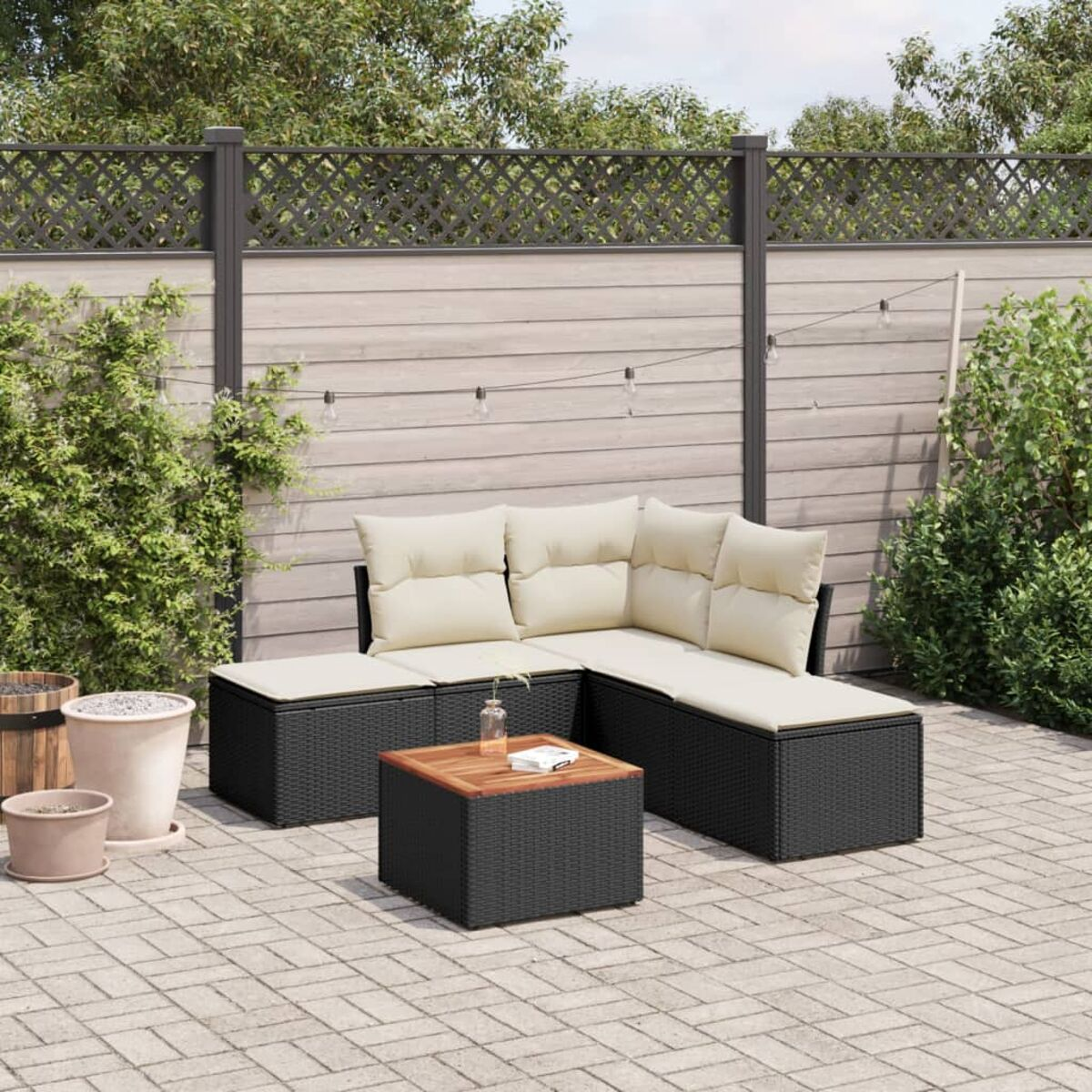 Schwarzes Rattansofa-Set mit cremefarbenen Kissen und Tisch, Terrasseneinstellung.