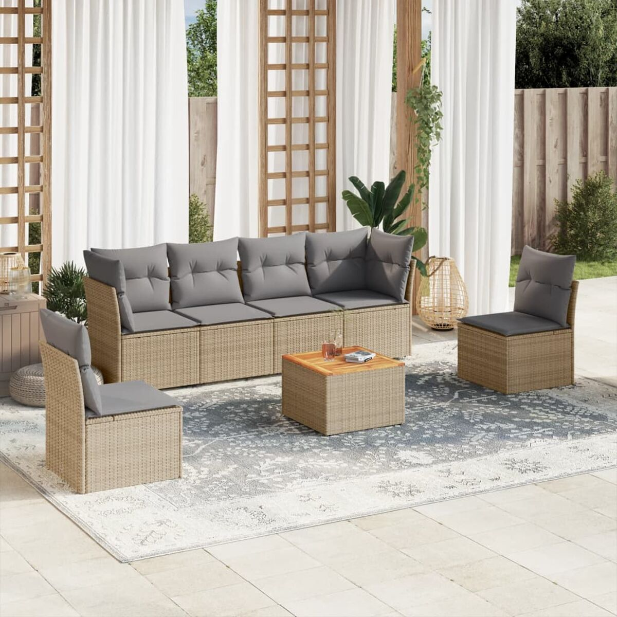 Rattan-Sofa-Set mit grauen Kissen, Couchtisch und zwei Stühlen, auf einer Terrasse mit Vorhängen.