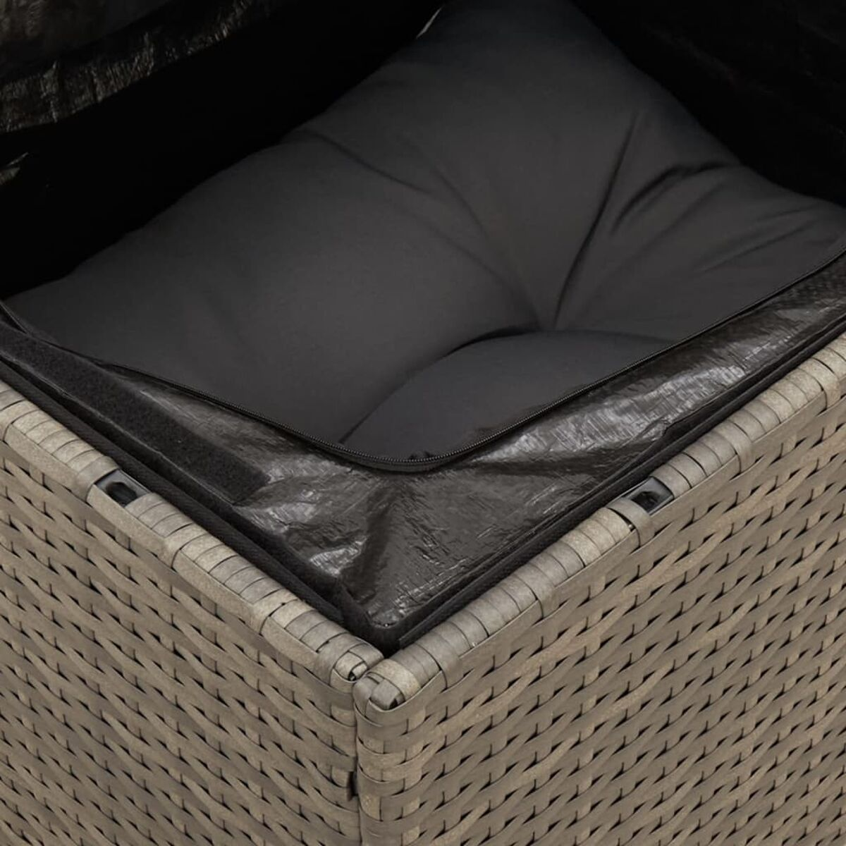 Nahaufnahme eines grauen Rattan-Outdoormöbelstücks. Ein schwarzes Kissen ist innen.