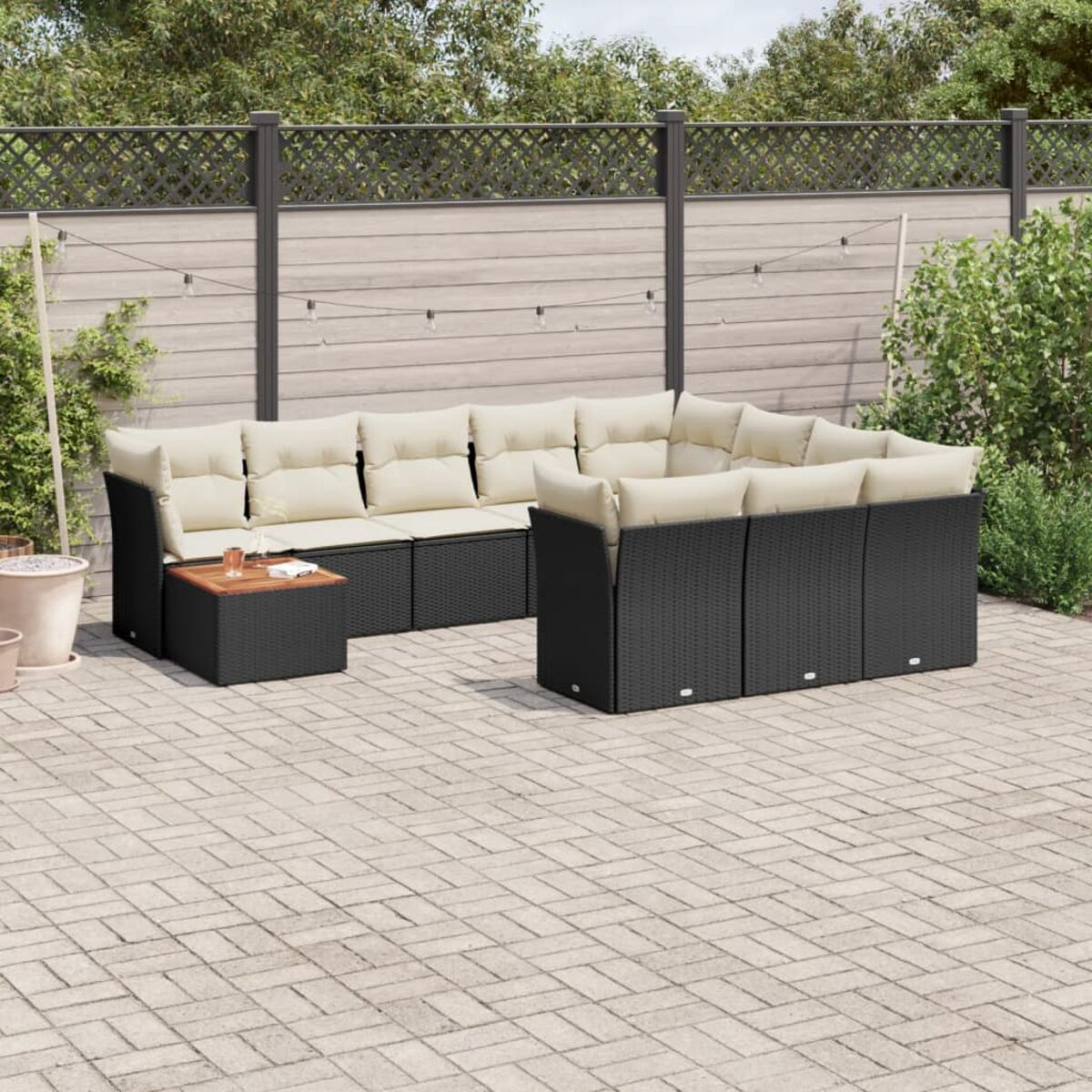 Schwarzes Outdoor-Ecksofa mit beigen Kissen, Holztisch, auf der Terrasse.