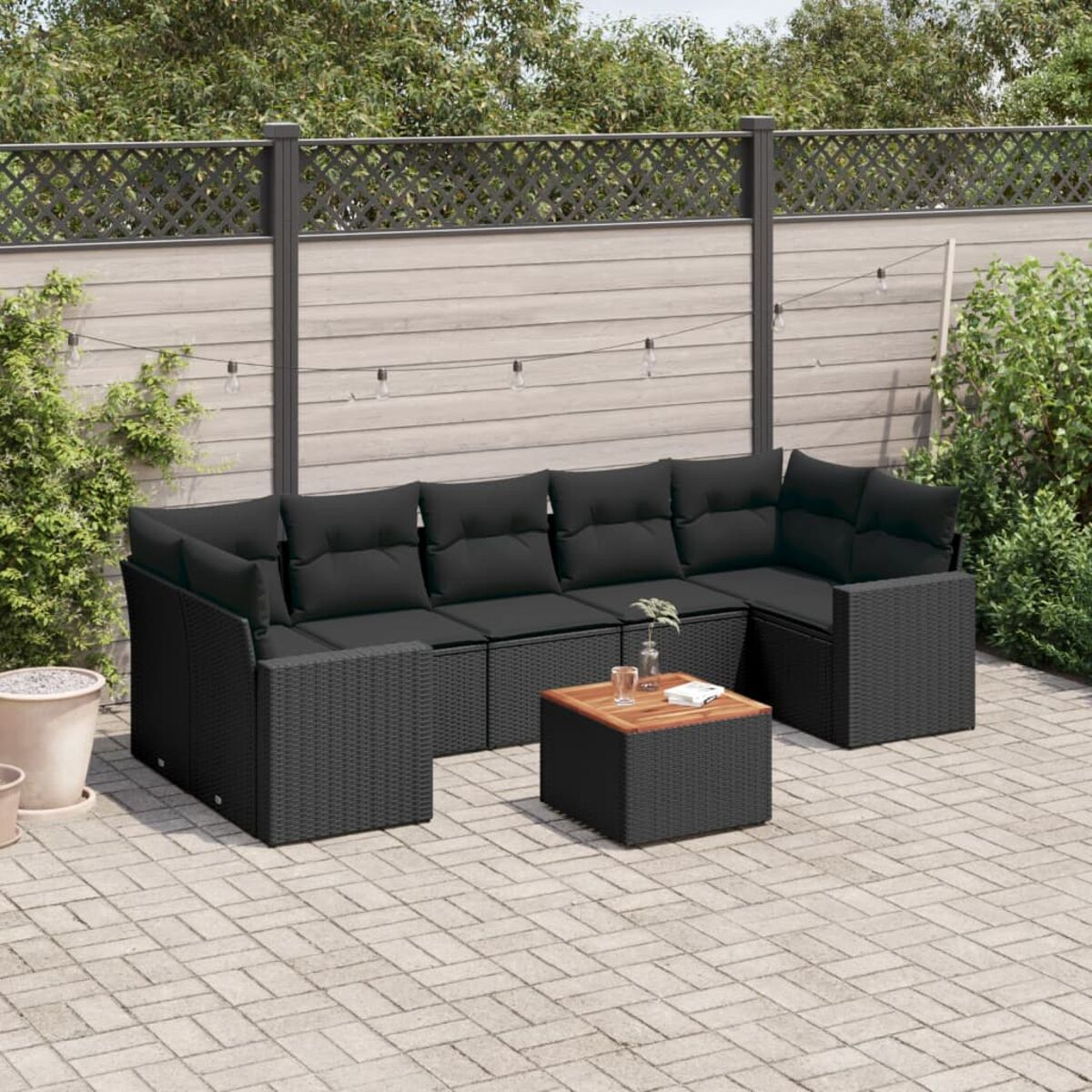 Schwarzes Outdoor-Ecksofa mit schwarzen Kissen und einem kleinen Tisch auf einer Terrasse.