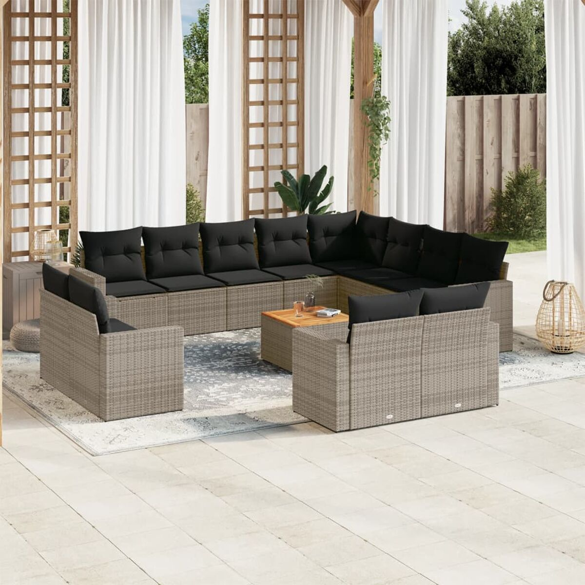 Rattan-Ecksofa mit schwarzen Kissen und Holztisch auf Terrassenplatten.
