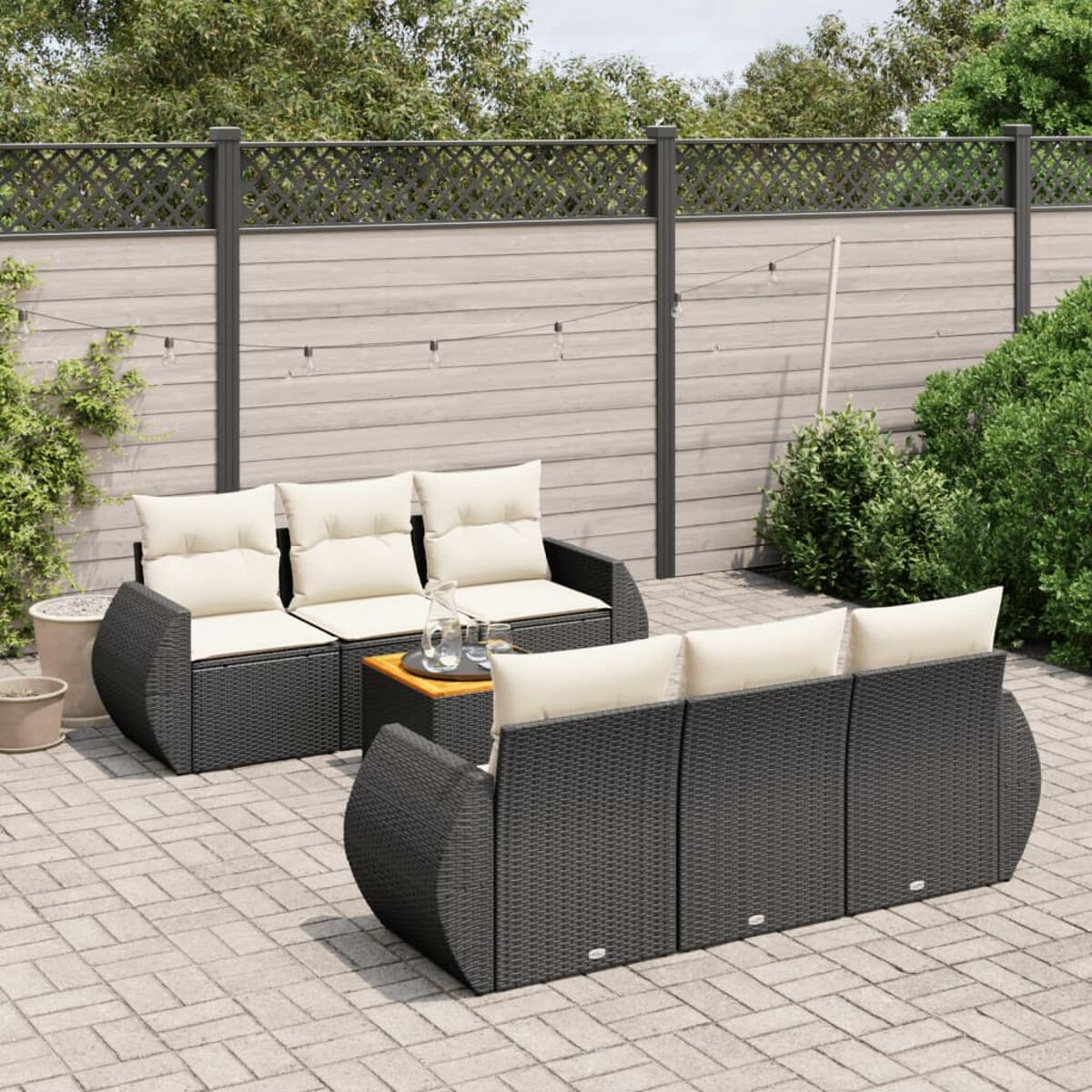 Terrassenmöbel-Set im Freien mit schwarzen Korbmöbeln, cremefarbenen Kissen und einem quadratischen Tisch.