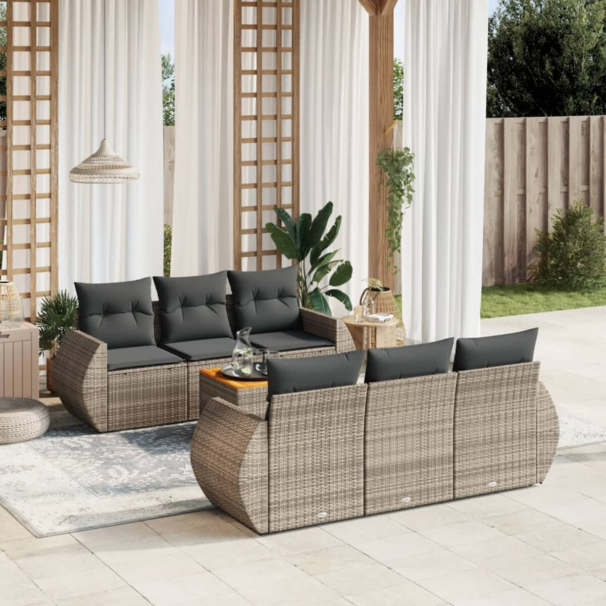 Outdoor-Sofaset mit grauen Kissen, Couchtisch und Teppich, mit weißen Vorhängen und Holzdekor.
