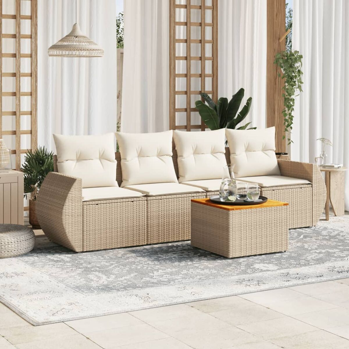 Outdoor-Korbsessel-Set mit cremefarbenen Kissen und einem Couchtisch auf einem Teppich, in der Nähe von Vorhängen und einem Gitter.