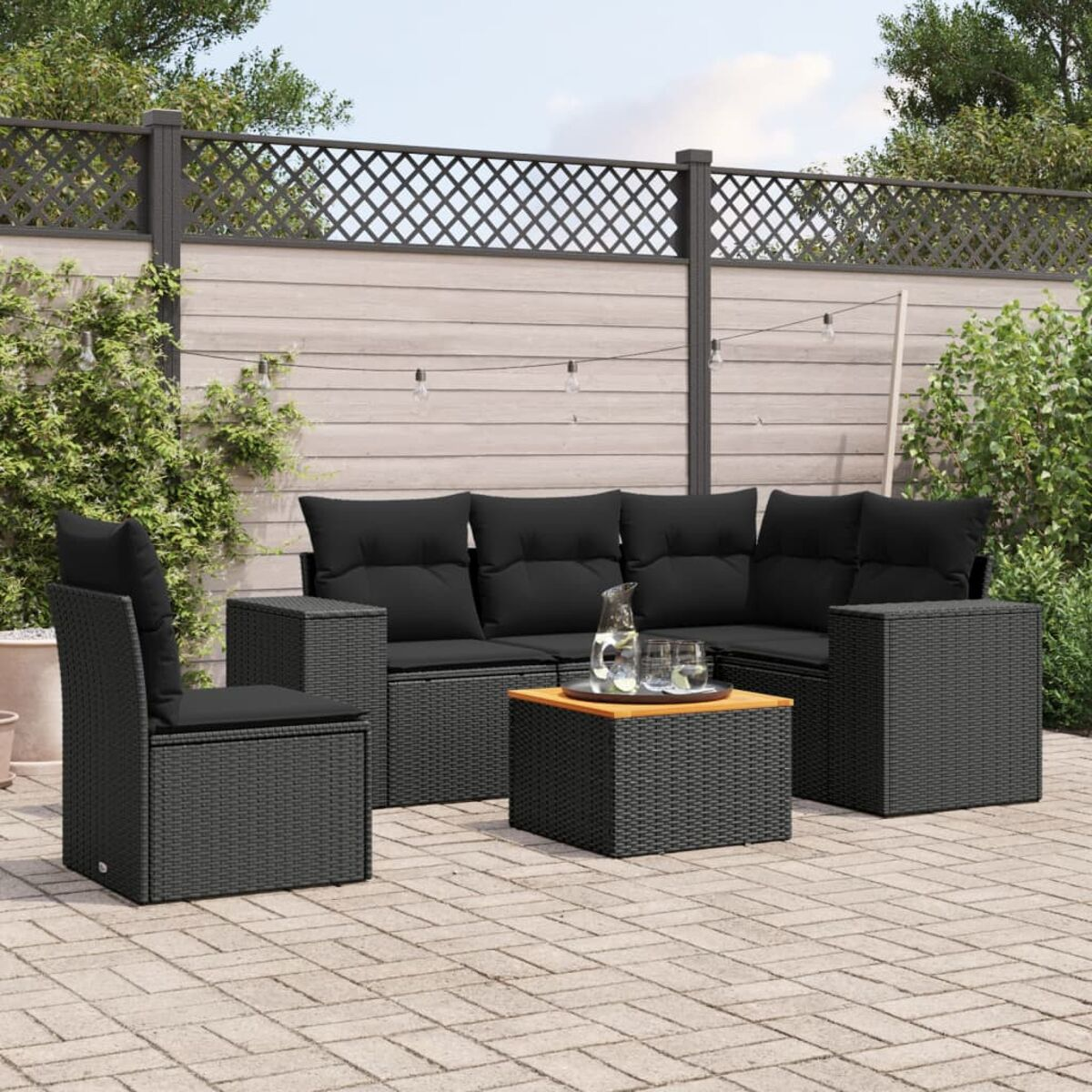 Schwarzes Outdoor-Geflecht-Ecksofa und Stuhl-Set mit schwarzen Kissen und einem quadratischen Tisch auf einer Terrasse.