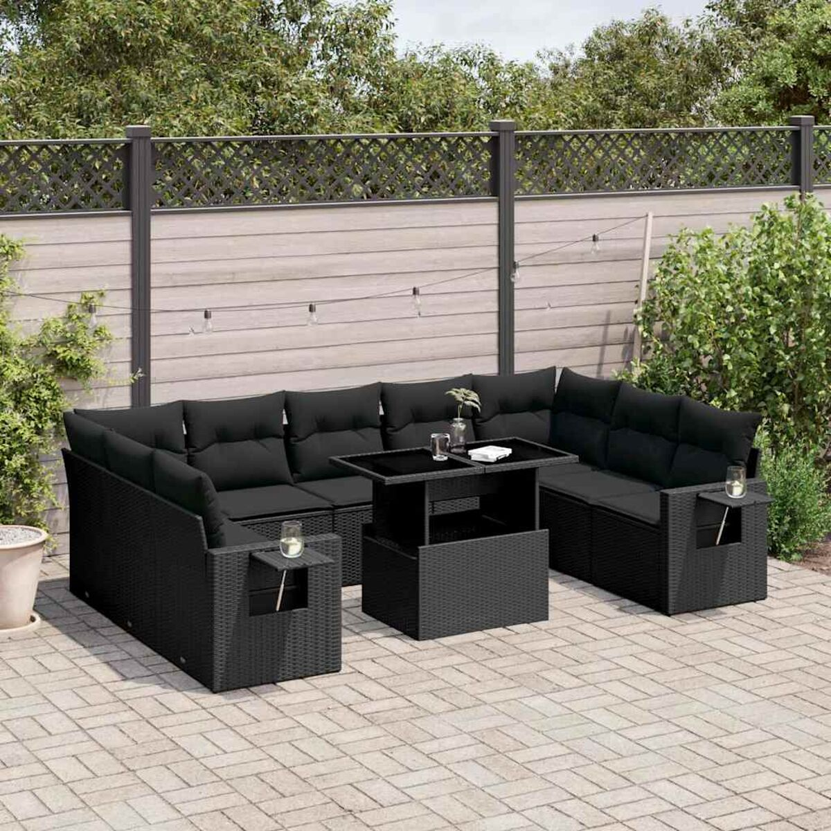 Schwarzes Ecksofa aus Korbgeflecht mit schwarzen Kissen und Tisch im Garten.