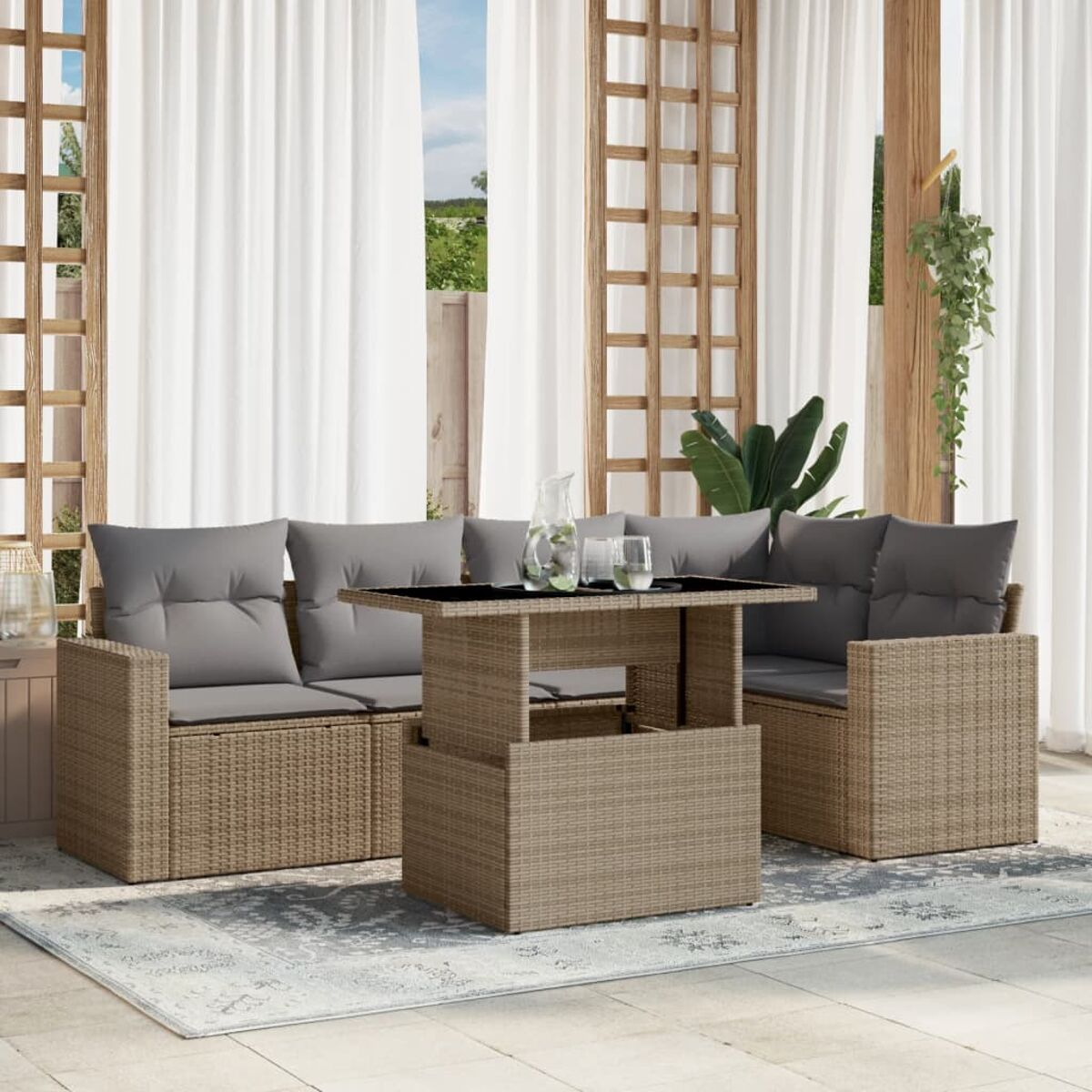 Gartenmöbel-Set aus Korbgeflecht mit grauen Kissen, Tisch mit Getränken. Vorhänge und Pflanzen im Hintergrund.