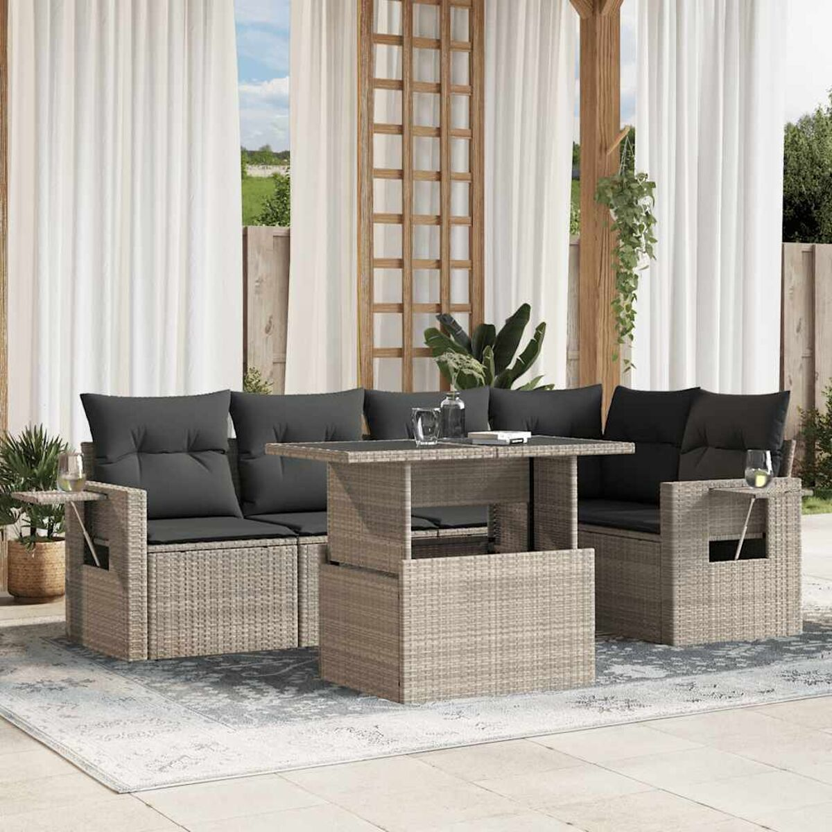 Rattan-Sofa-Set für den Außenbereich mit schwarzen Kissen und passendem Tisch, auf einer Terrasse.