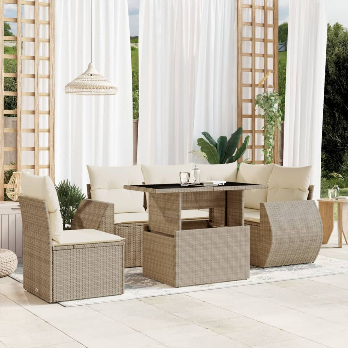 Set divani da esterno. Vimini beige con cuscini color crema e un tavolo, su un tappeto, in giardino.
