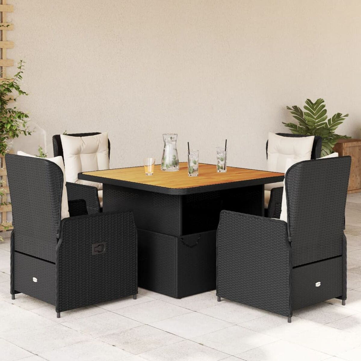 Schwarzes Outdoor-Sitzset aus Rattan mit Holztisch und weißen Kissen. Getränke auf dem Tisch.
