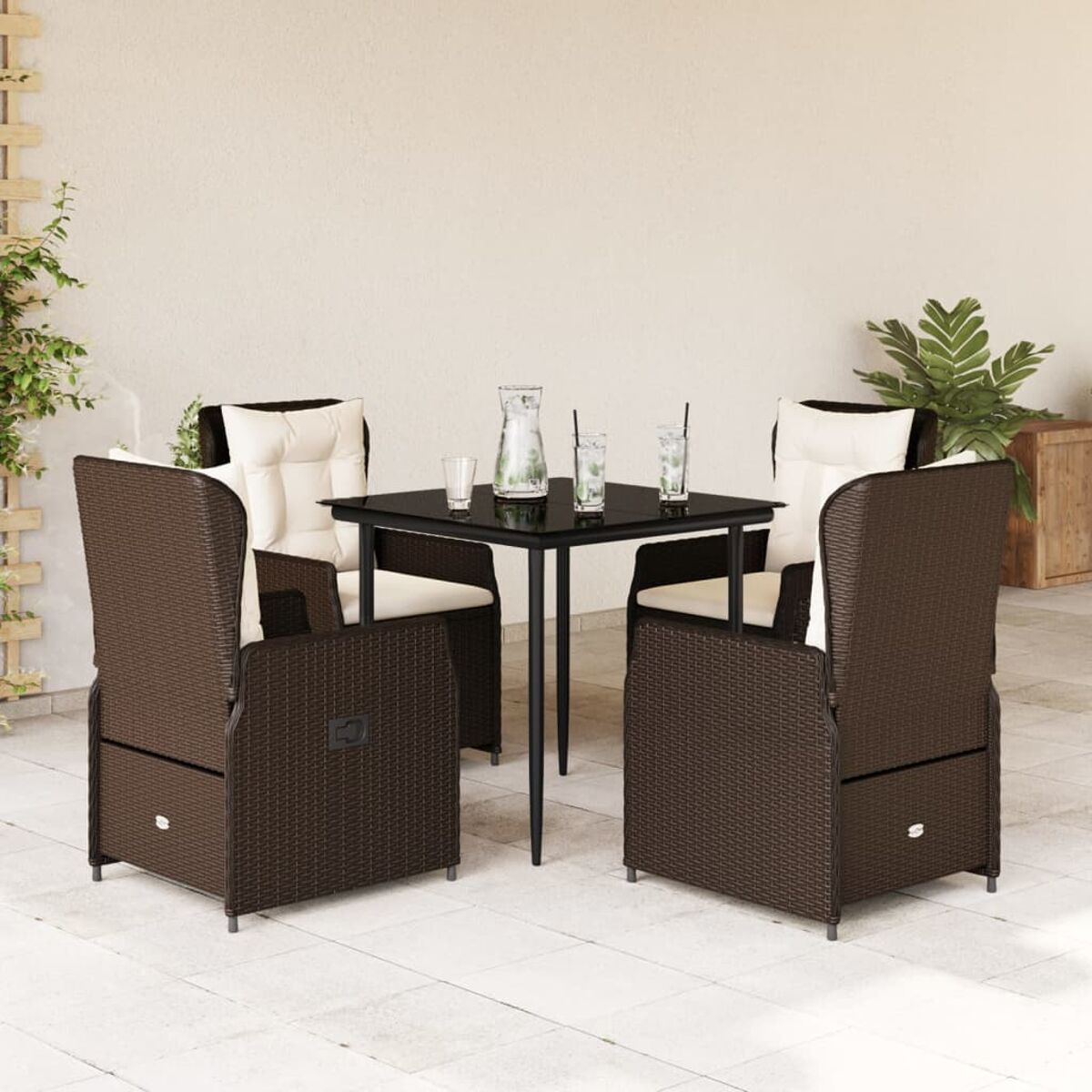 Sedie in rattan marrone con cuscini beige attorno a un tavolo nero con bicchieri e una brocca.