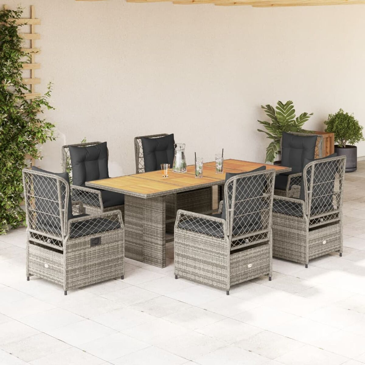 Essgruppe für den Außenbereich mit grauen Korbstühlen, dunklen Kissen und einem Holztisch auf einer Terrasse.