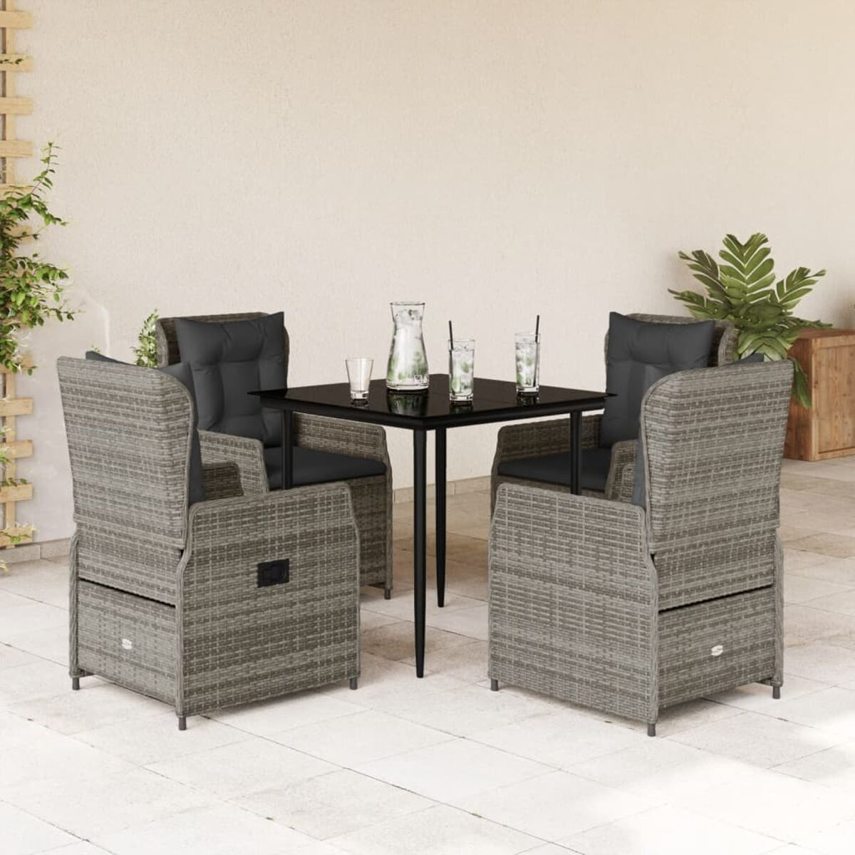 Set da esterno con sedie in rattan grigio, un tavolo e bevande. Cuscini neri.