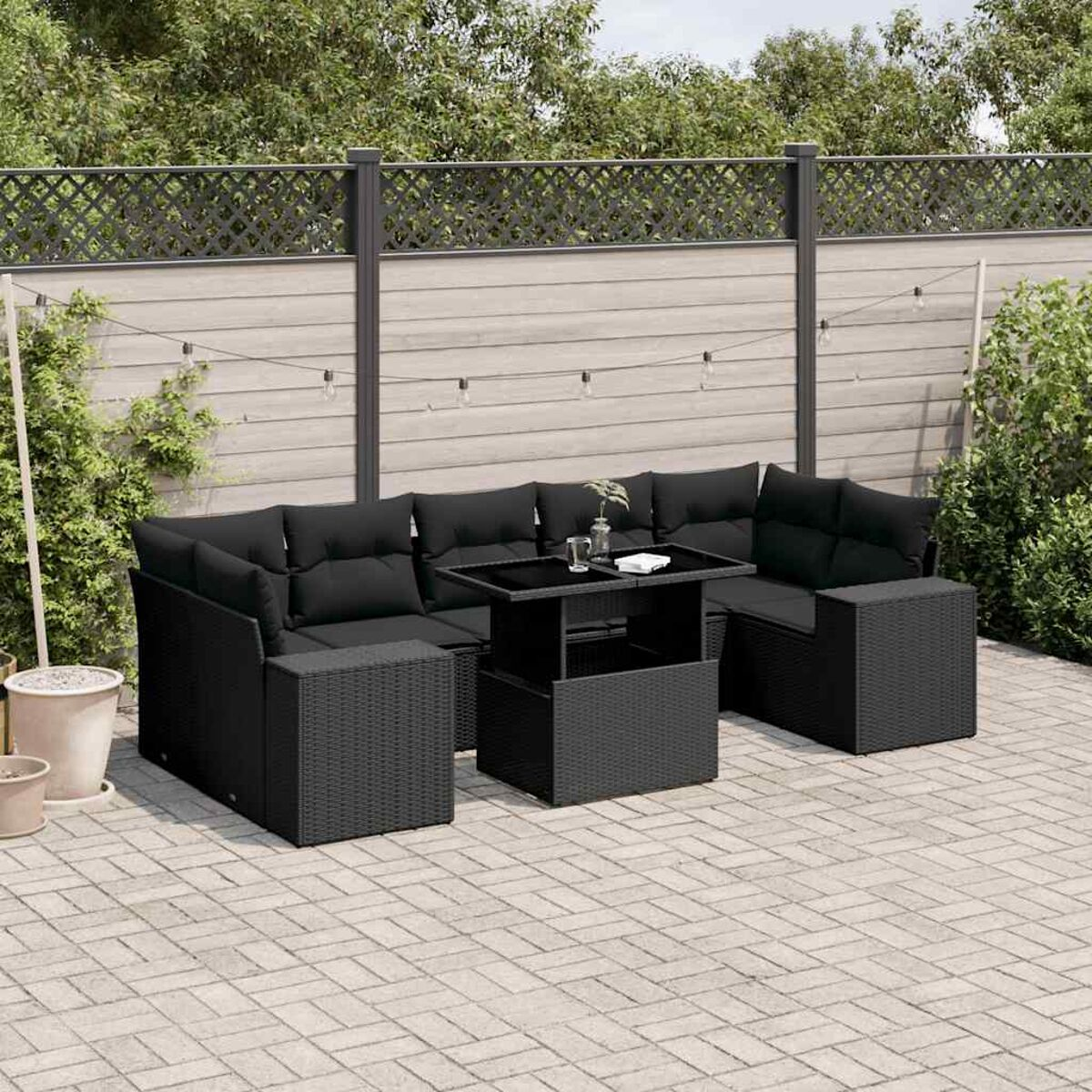 Schwarzes Outdoor-Möbelset aus Korbgeflecht mit Tisch und Kissen.
