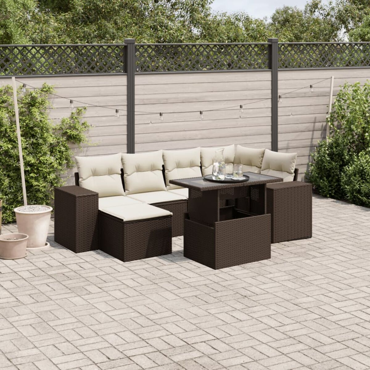 Eine Terrasse mit einem braunen Rattan-Sofa, einem schwarzen Tisch und einem Ziegelboden.