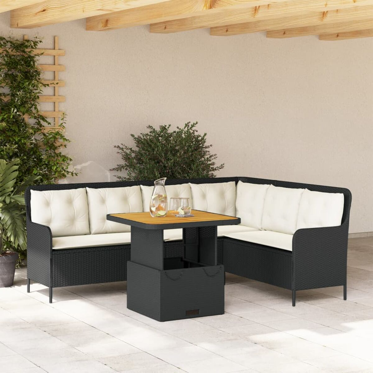 Ein schwarzes Rattan-Ecksofa mit weißen Kissen und einem Couchtisch mit Holzplatte auf einer Terrasse. Pflanzen und Grün.