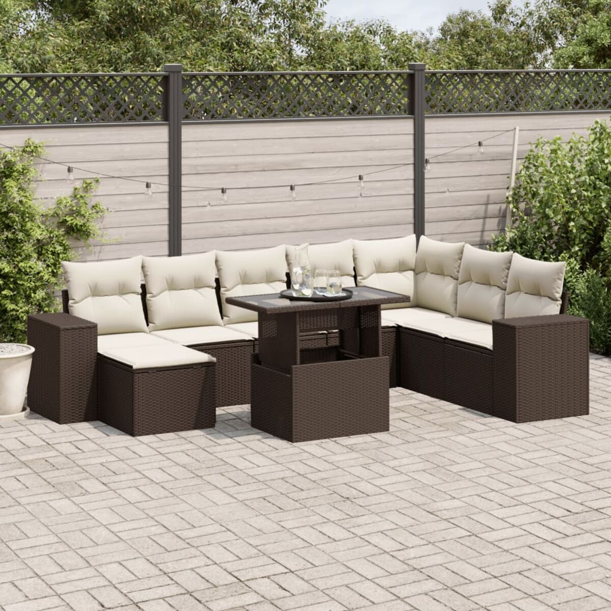 Braunes Rattan-Ecksofa mit beigen Kissen, Glastisch und Außenbereich. Holzzaun im Hintergrund.