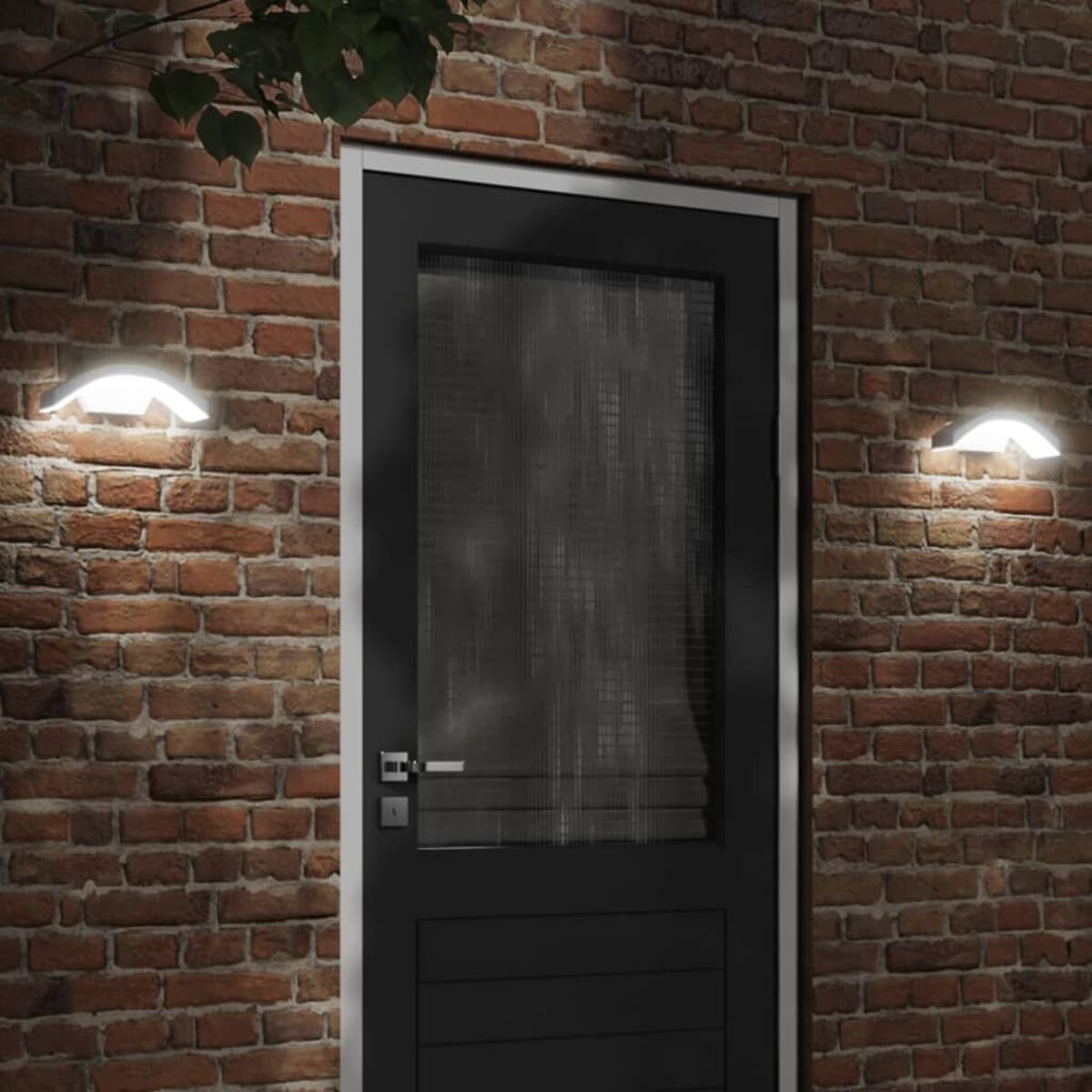 Außenansicht: Backsteinmauer mit schwarzer Tür und weißen Wandlampen. Die Lampen haben ein geschwungenes Design.