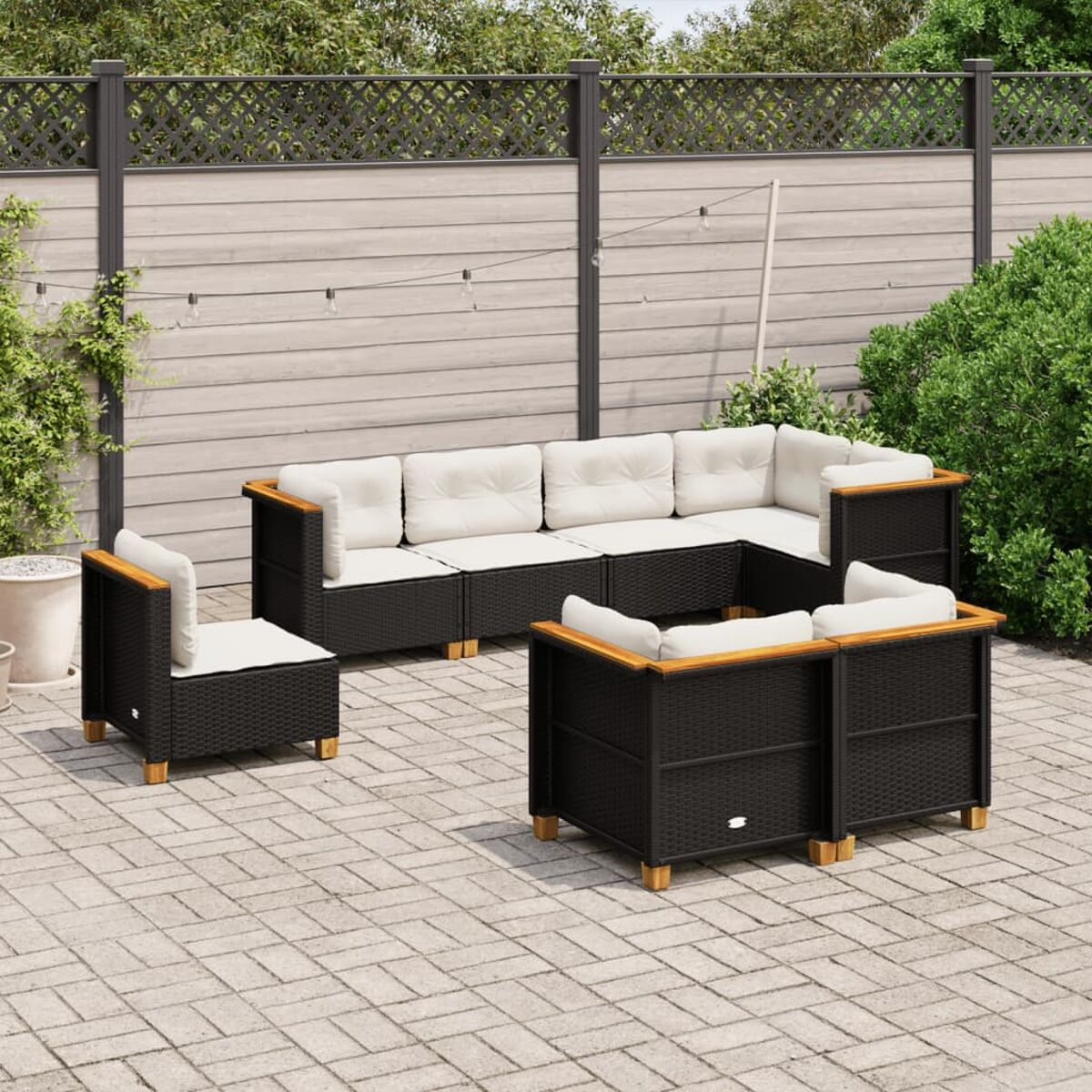Schwarzes Rattan-Gartenmöbel-Set: Sofa, zwei Stühle und ein Tisch, auf einer Ziegelterrasse.
