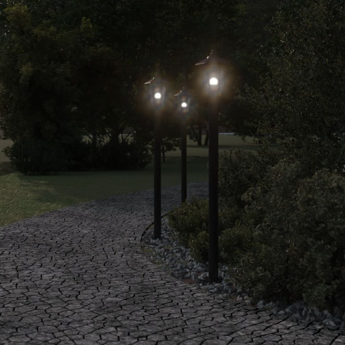 Drei beleuchtete Laternenpfähle säumen einen geschwungenen Kopfsteinpflasterweg, umgeben von dunkelgrünen Büschen und Bäumen bei Nacht.