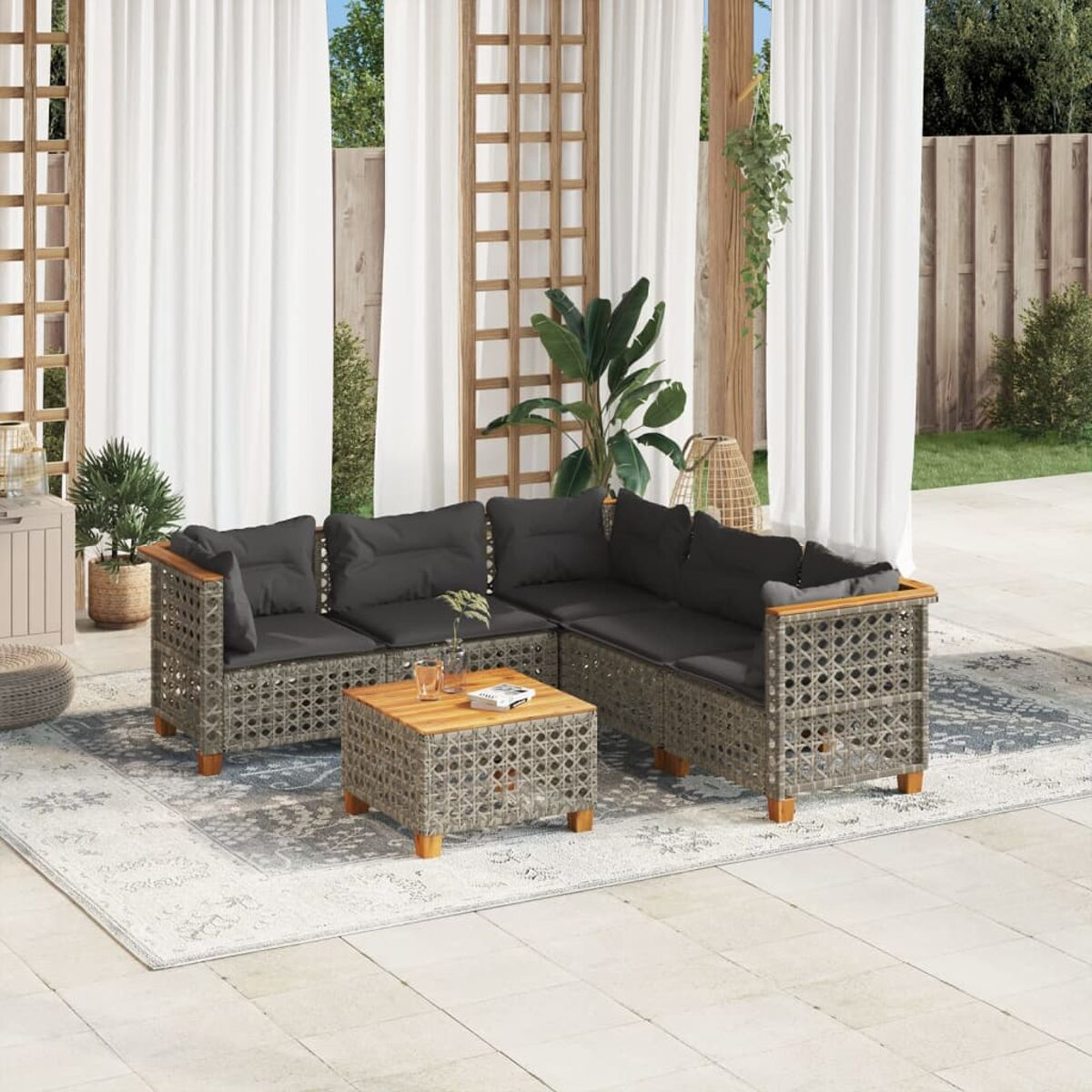 Outdoor-Rattansofa-Set mit schwarzen Kissen, einem Tisch und einem Stuhl, auf einem Teppich.