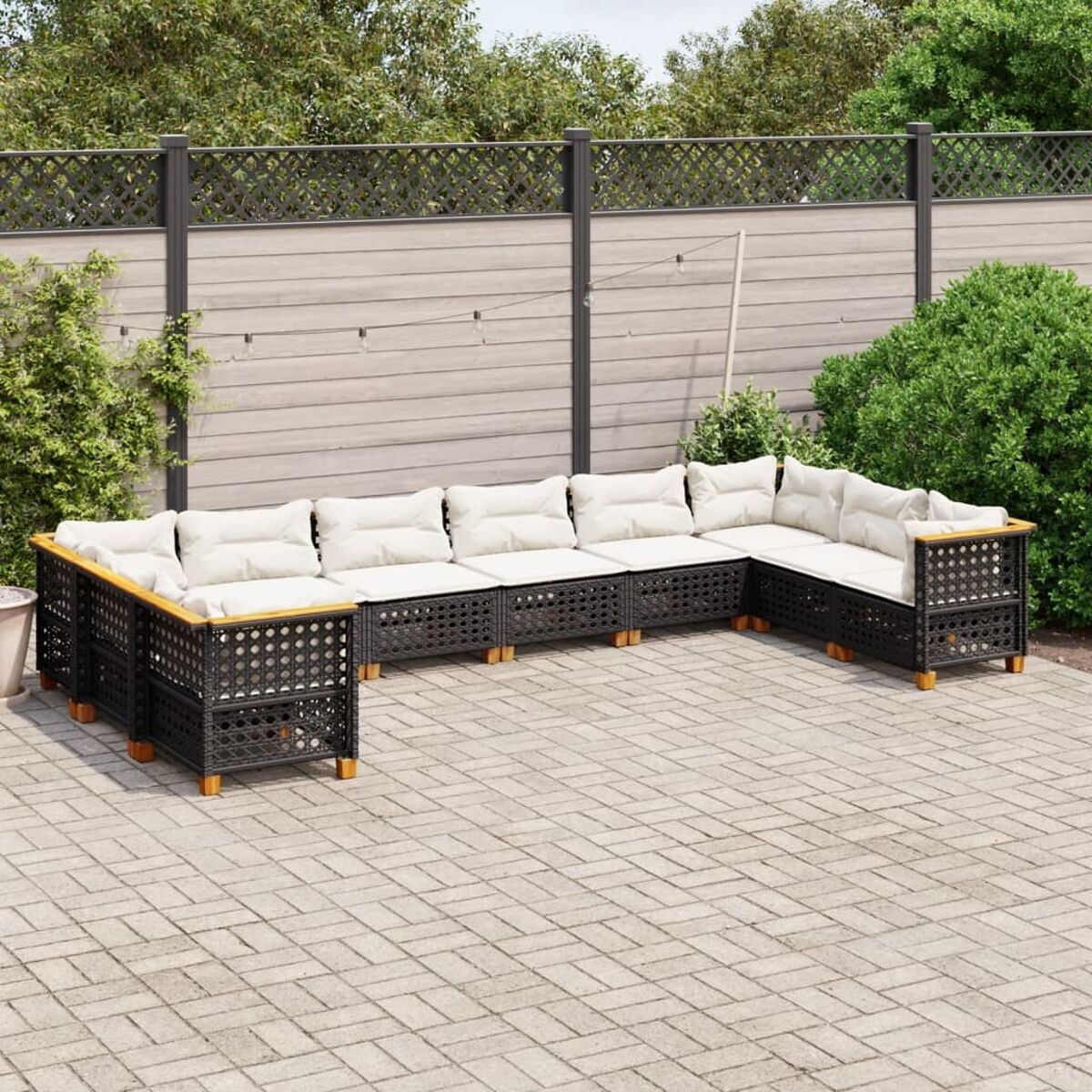 Schwarzes und braunes Outdoor-Ecksofa auf einer Ziegelterrasse, mit Holzzaun im Hintergrund.