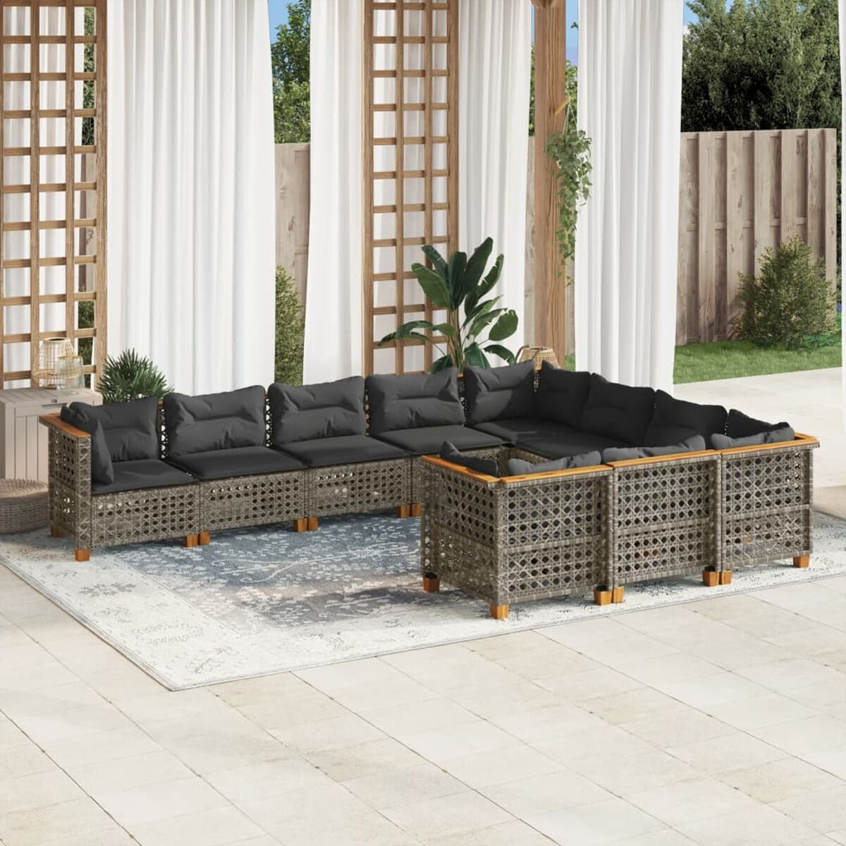 Graues Outdoor-Möbelset aus Korbgeflecht; Ecksofa, Tisch und Stühle auf einer Terrasse mit Pflanzen.