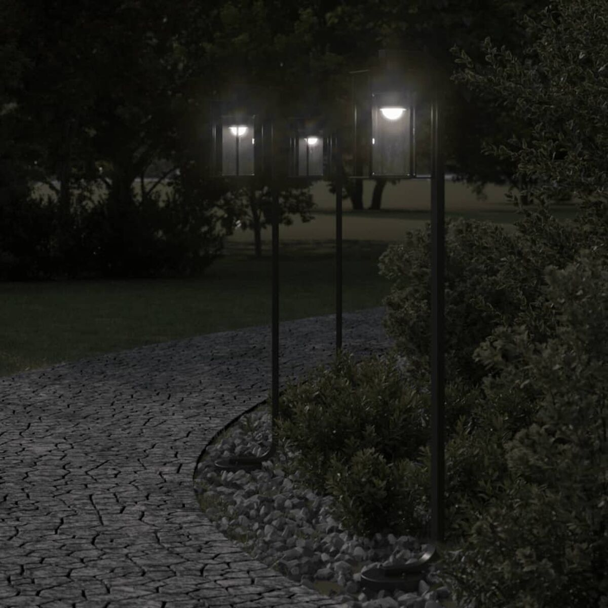 Sentiero con tre luci esterne fiancheggiate da cespugli, di notte.