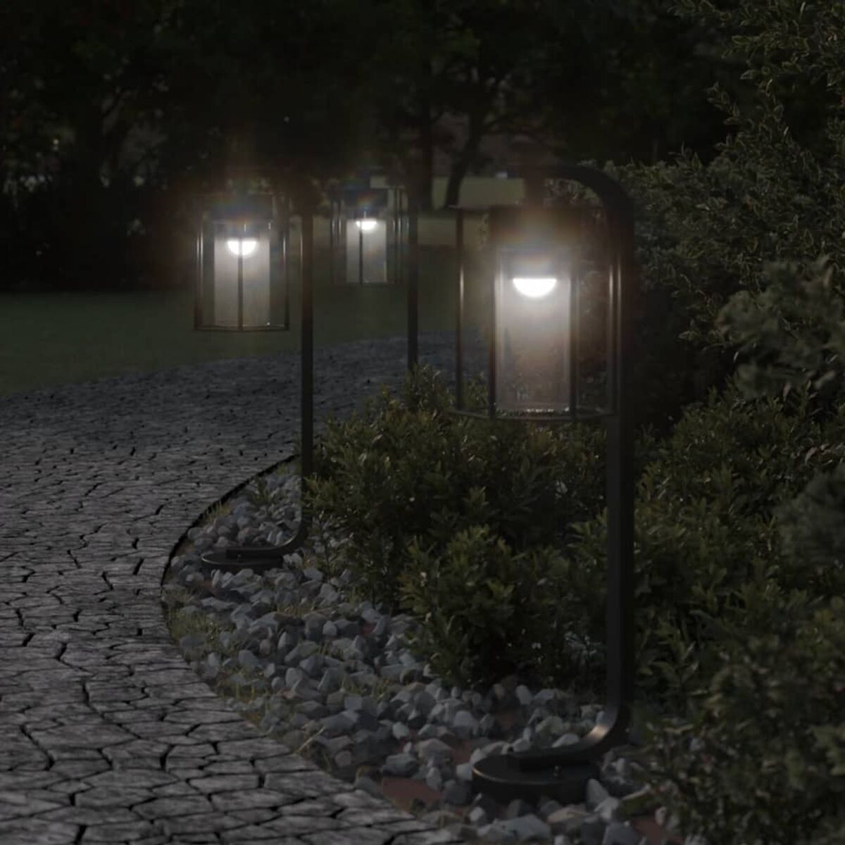 Tre luci esterne lungo un sentiero di pietra di notte. Cespugli e alberi verdi sullo sfondo.